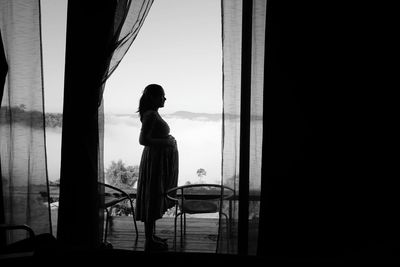 Side view of woman looking through window