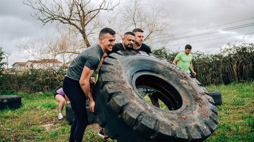 Male friends picking up tire at boot camp