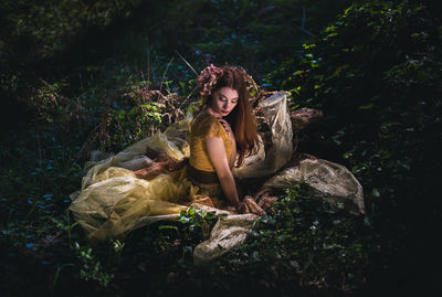 Young woman sitting on tree in forest