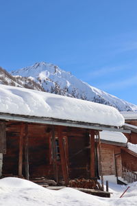 Snow covered houses by mountain against sky