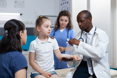 Doctor applying bandages on patient arm at clinic