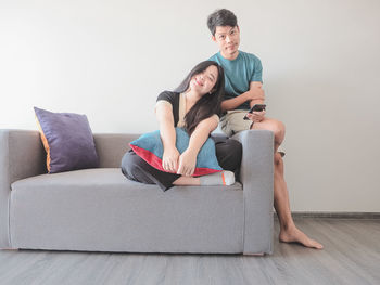 Portrait of smiling couple sitting on sofa at home