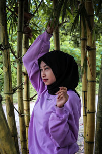 Portrait of woman standing against purple tree