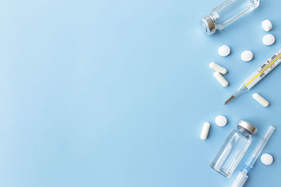 Medicine treatment. thermometer, vaccine bottles, injection, syringe, pills on blue background