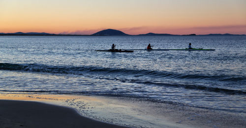 Silhouette people on beach against sky during sunset