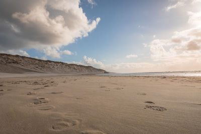 Scenic view of sand dunes against sky