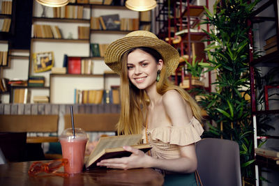 Portrait of smiling young woman sitting at restaurant table