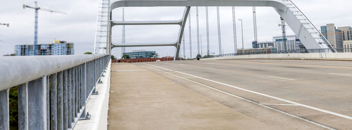 Road by bridge in city against sky