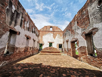 Low angle view of old building against cloudy sky