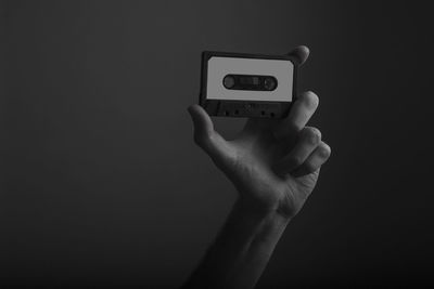 Close-up of hand holding telephone against black background