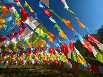 Low angle view of multi colored flags hanging against sky