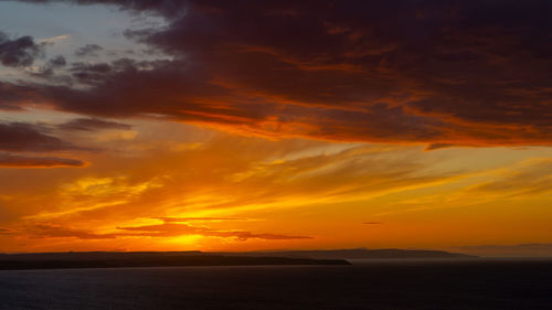 Scenic view of sea against dramatic sky during sunset