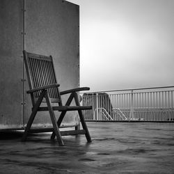 Empty chairs and table by sea against clear sky