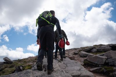 Rear view of men on rock against sky