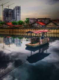 Boat moored on water in city against sky