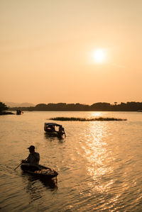 People in boat on sea against sky during sunset