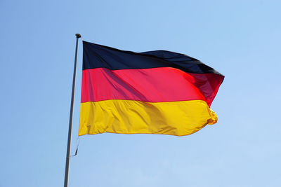 Low angle view of german flag against clear blue sky