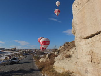 Hot air balloons flying over rock formation against sky