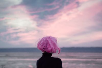 Rear view of woman against pink sky