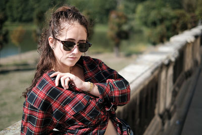 Portrait of young woman wearing sunglasses while standing outdoors
