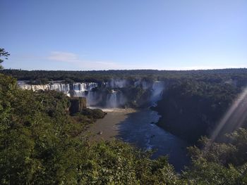 Scenic view of waterfall against clear blue sky