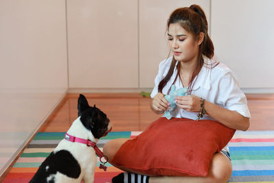 Portrait of woman with dog sitting at home