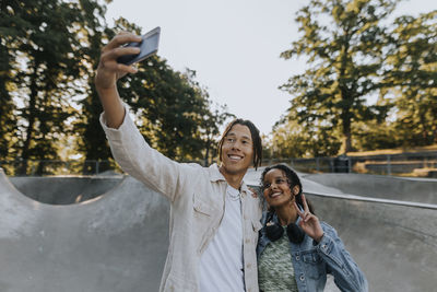 Smiling teenagers taking selfie at skate park