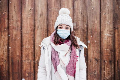 Caucasian woman wearing face mask outdoors in city while snowing in winter. pandemic corona virus
