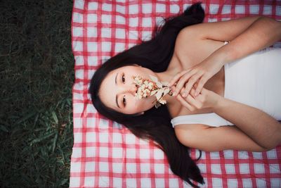 Directly above shot of woman with flowers lying on blanket over grass