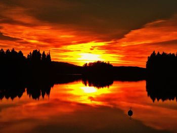 Scenic view of dramatic sky over silhouette trees during sunset