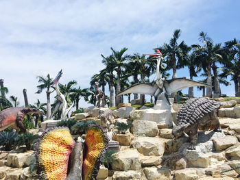 Palm trees by rocks against sky