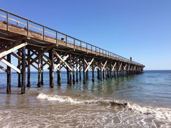 Pier over sea against clear blue sky