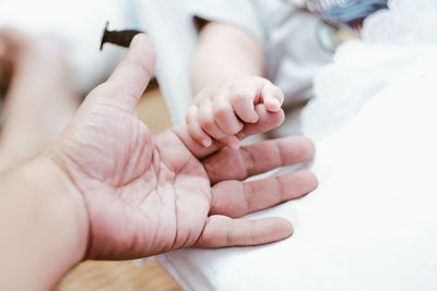 Cropped hand of baby on bed