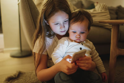 Girl showing baby sister cell phone