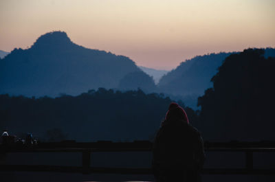 Rear view of silhouette woman looking at mountains against sky