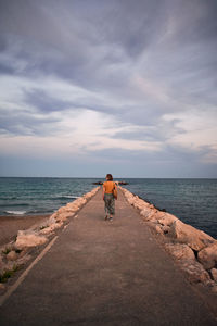 Rear view of man riding bicycle on sea against sky