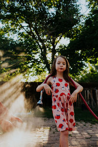 Young girl playing outside with garden hose