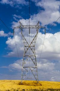 Low angle view of electricity pylon against cloudy sky