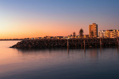 Reflection of buildings in sea at sunset