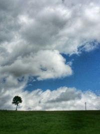 Scenic view of grassy field against cloudy sky