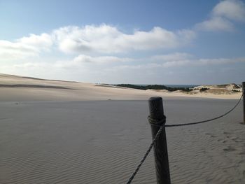 Sand dunes at beach against sky