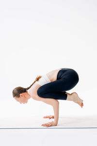 Full length of woman exercising against white background