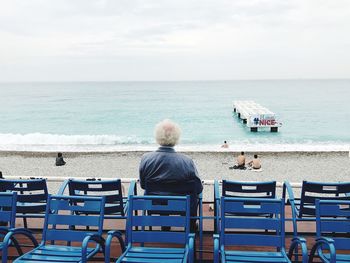 Rear view of people sitting on chair at beach