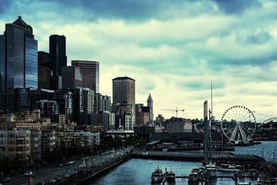 Boats at harbor against cloudy sky