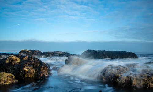 Scenic view of rocks in sea against sky