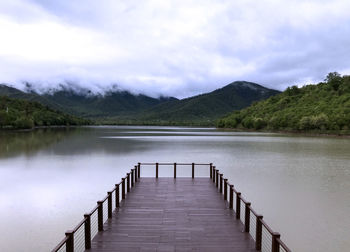 Wooden pier on lake against sky
