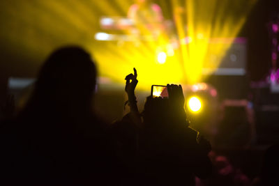 Silhouette person filming over smart phone at music concert