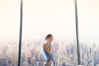 Woman standing by modern buildings in city