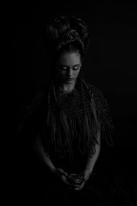 Portrait of young woman against black background