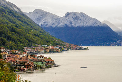 Town by lake and mountains against sky